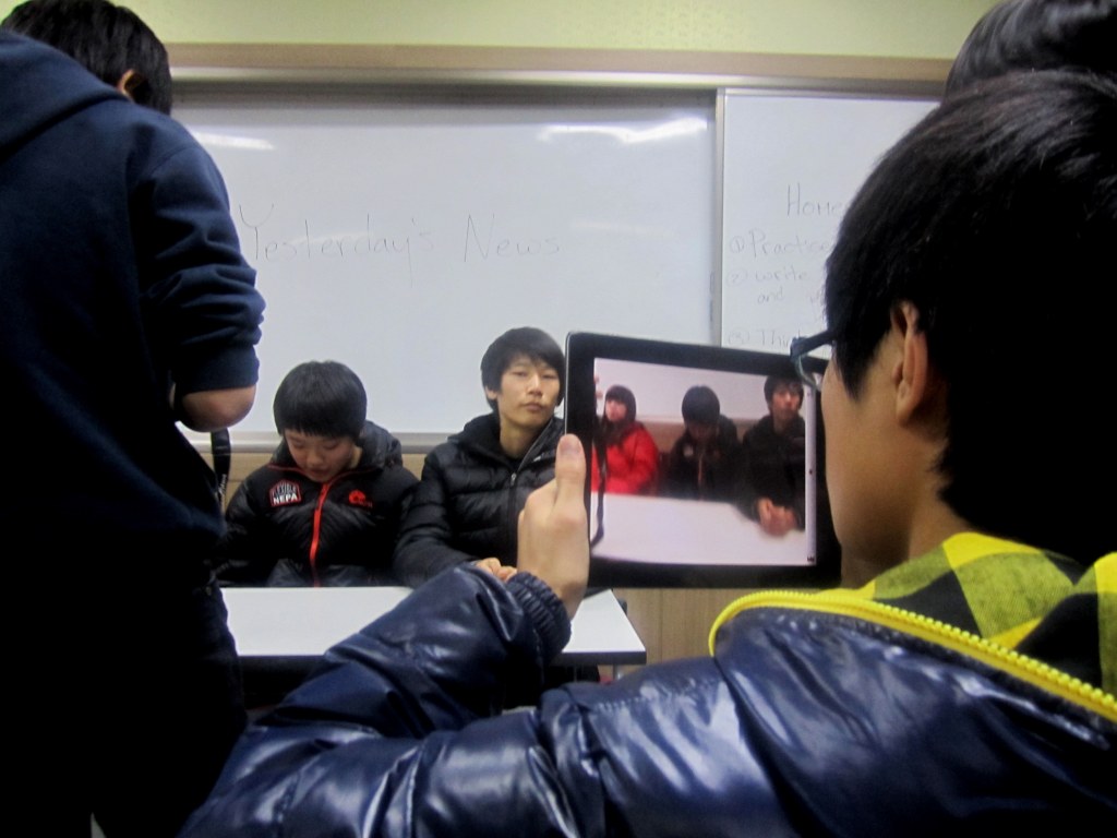 Korean middle school student holding an iPad prepares to film a news segment.